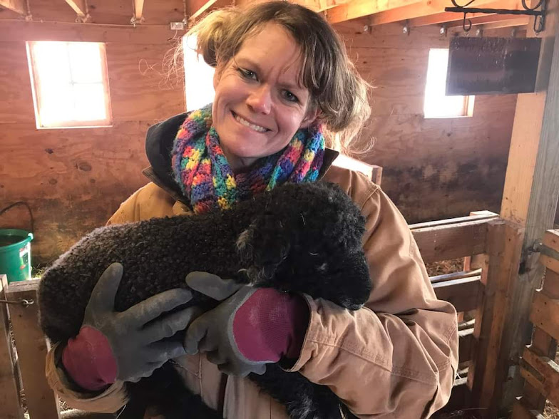 Owner, Keli, holding a black newborn lamb
